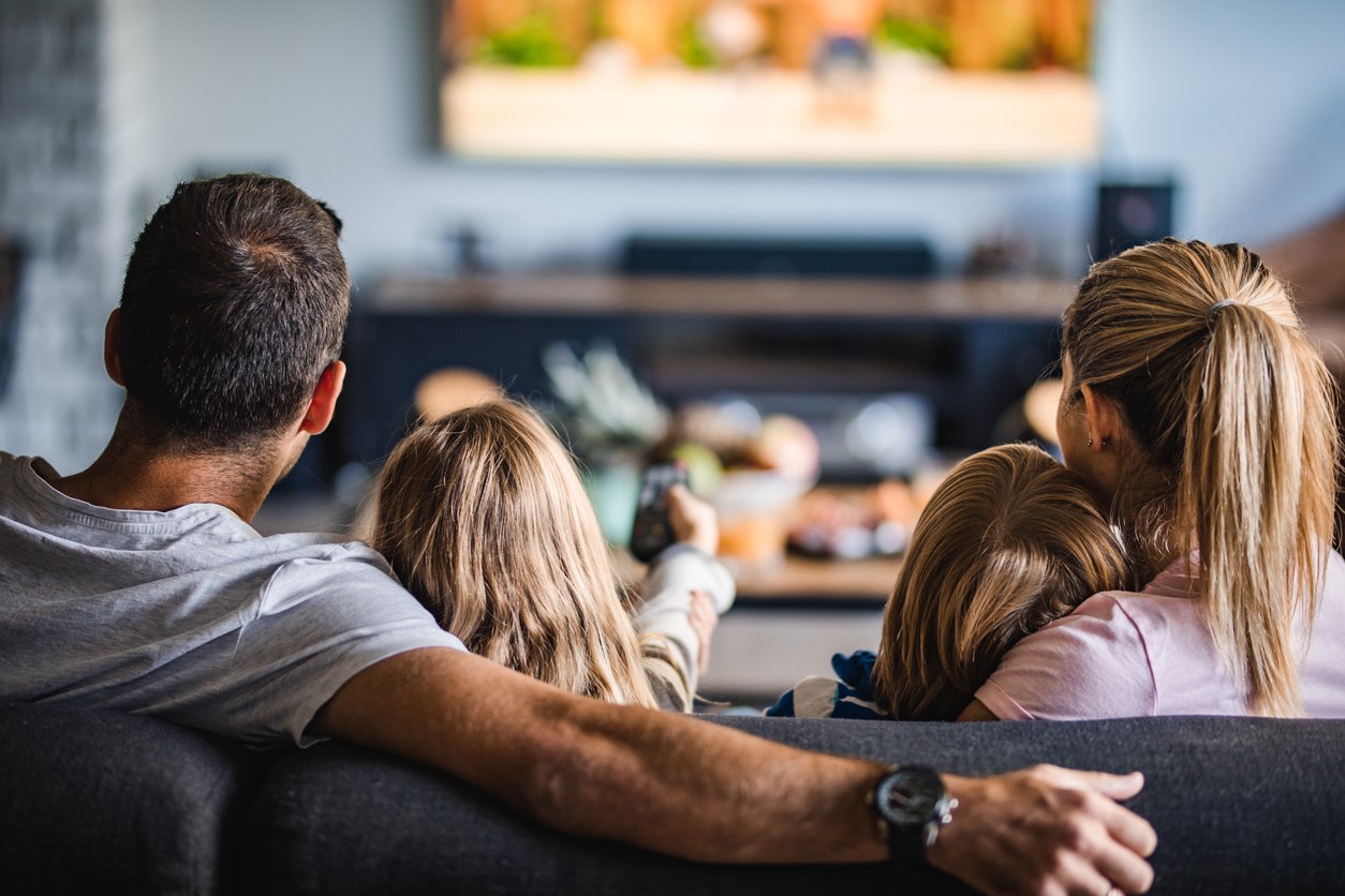 Familj som sitter i soffan och tittar på TV