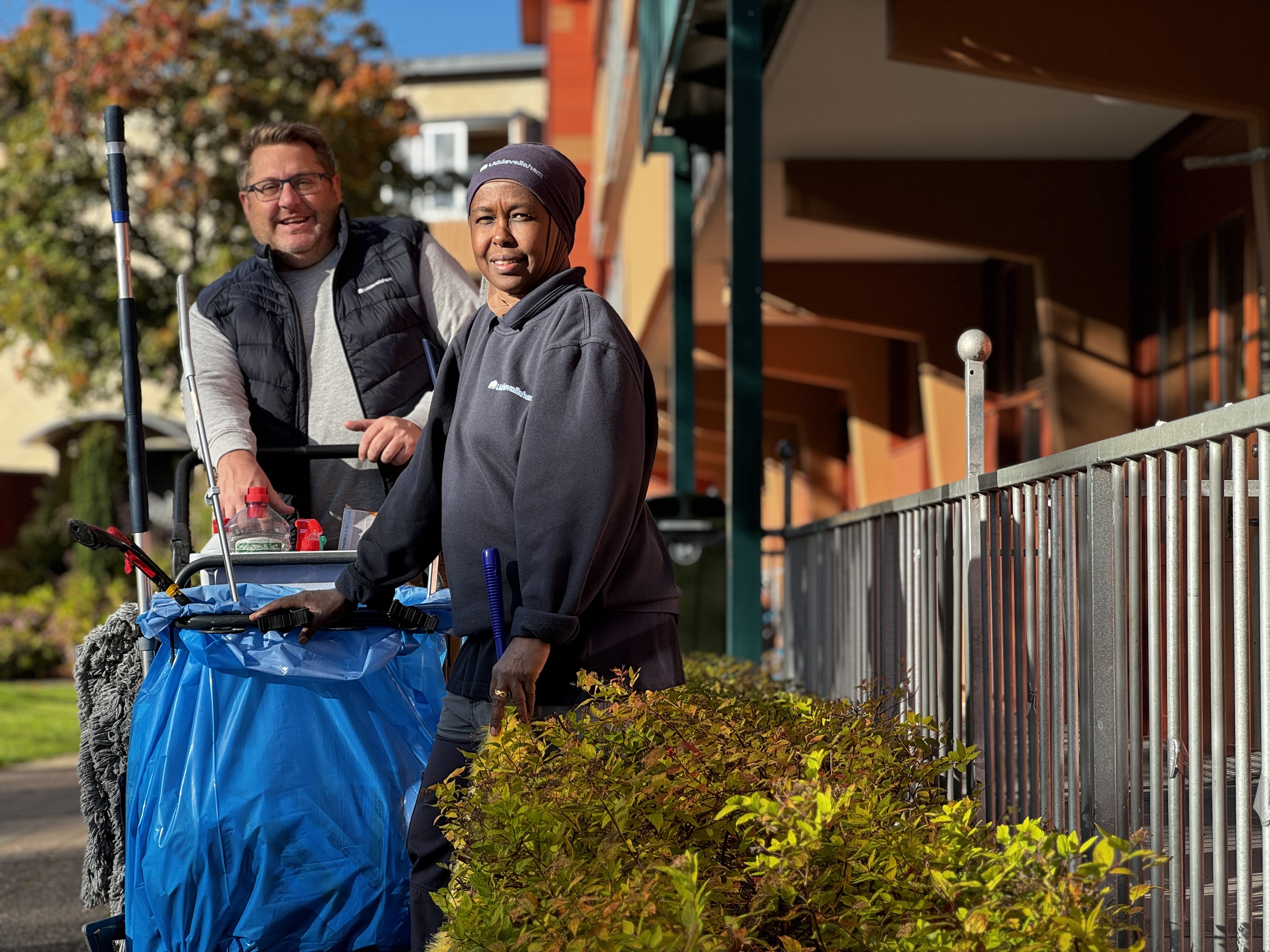 Två lokalvårdare som står vid en städvagn