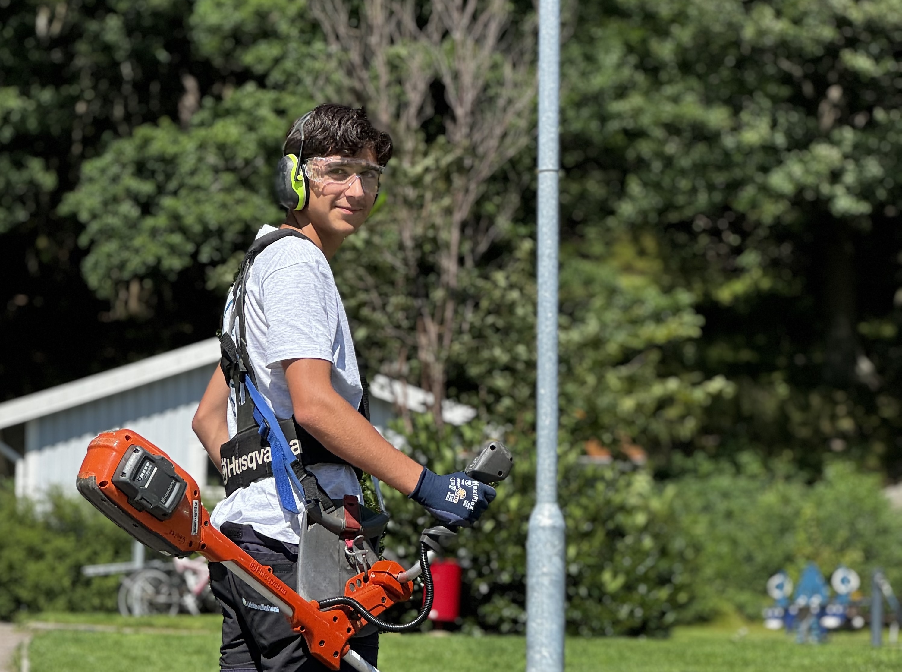 Sommarjobbare på Uddevallahem som håller i en grästrimmer