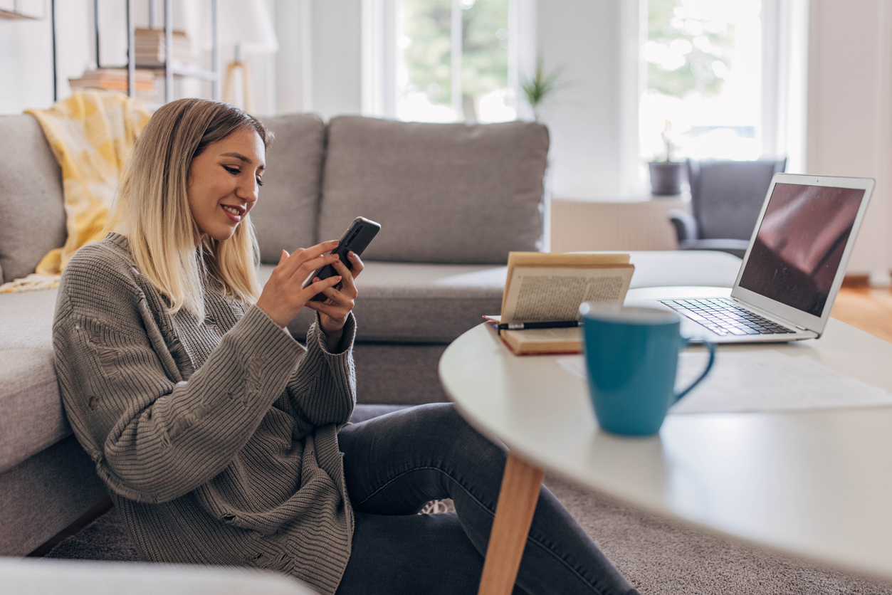 Kvinna som sitter på golvet med sin telefon