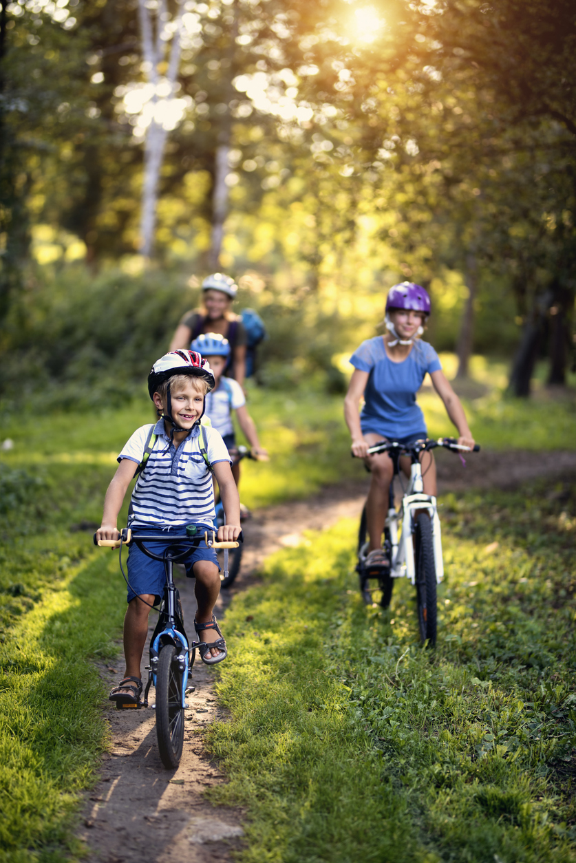 Familj som cyklar på en skogsstig