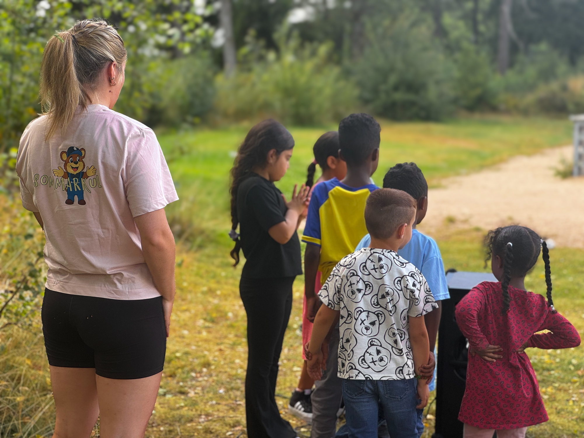 Aktivitetsvärd som hjälper barn som står i kö till karokemaskinen