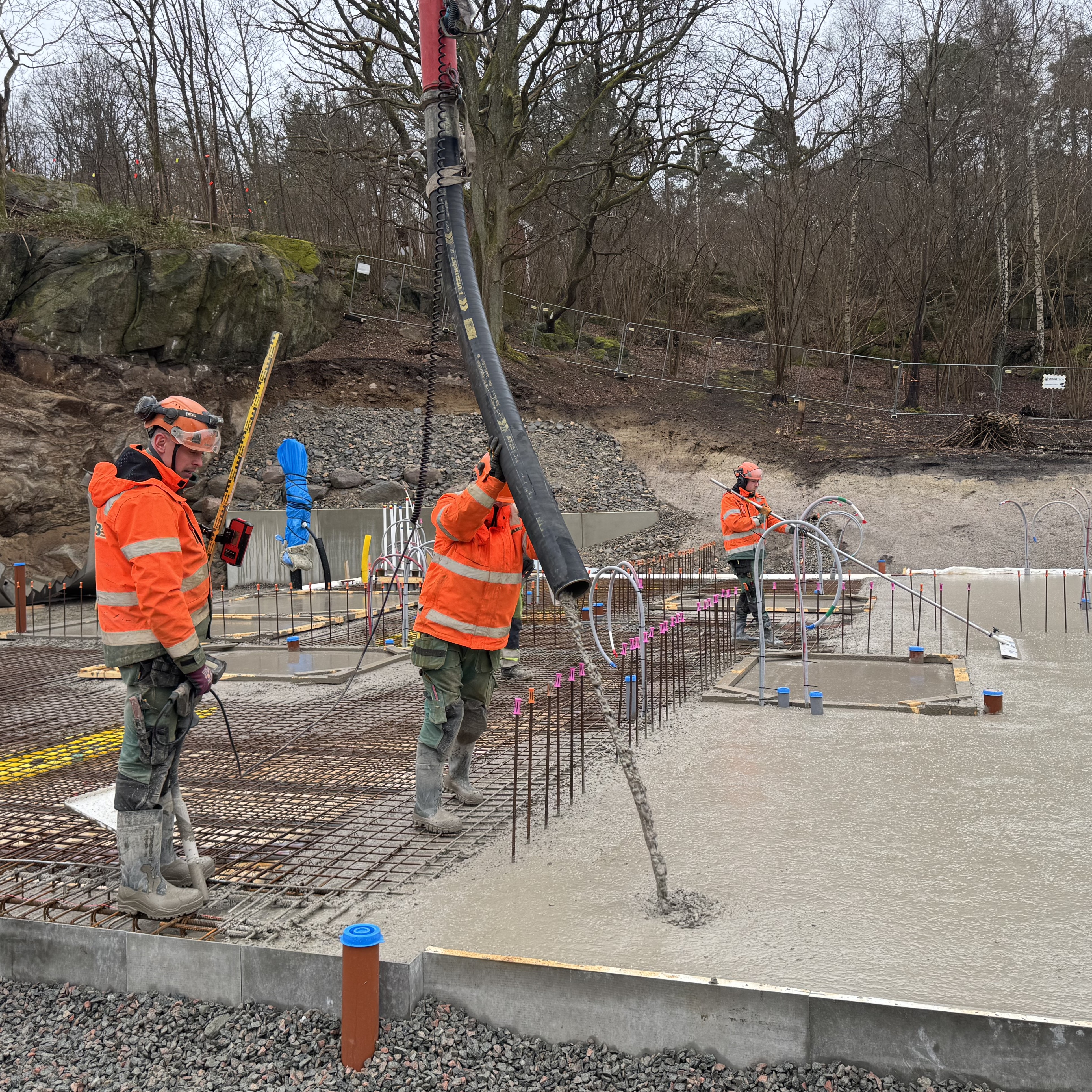 Tre män i varselkläder gjuter bottenplatta